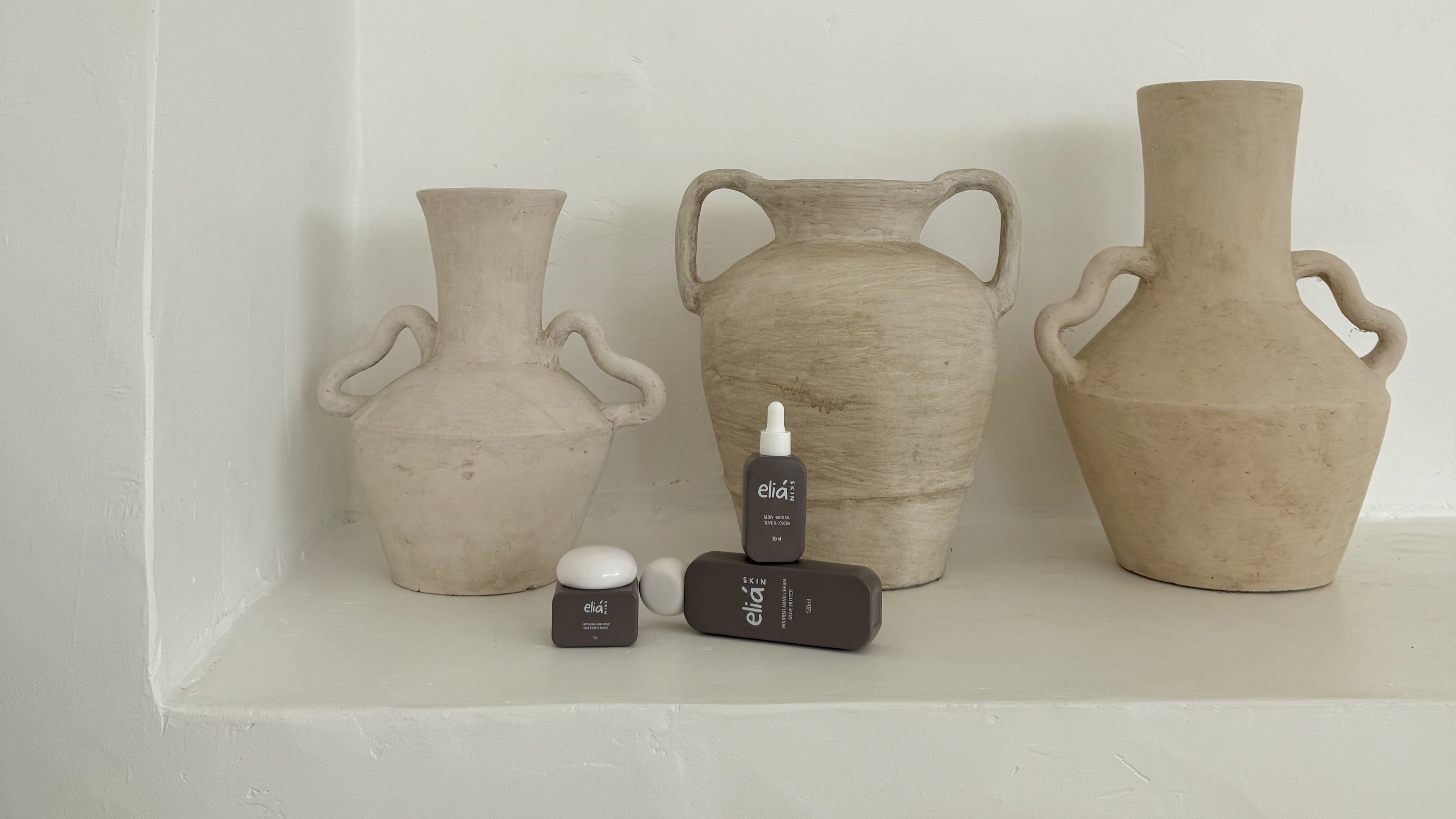 Three ceramic vases on a white shelf with a minimal background